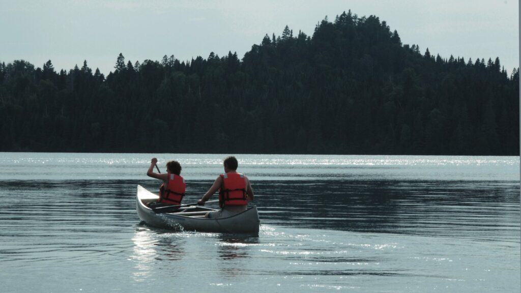 Two people canoeing with orange life vests on Lake Superior in Isle Royale National Park.