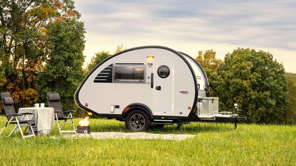 Tab Teardrop camper trailer by nuCamp in a campsite with camping chairs and a portable firepit.