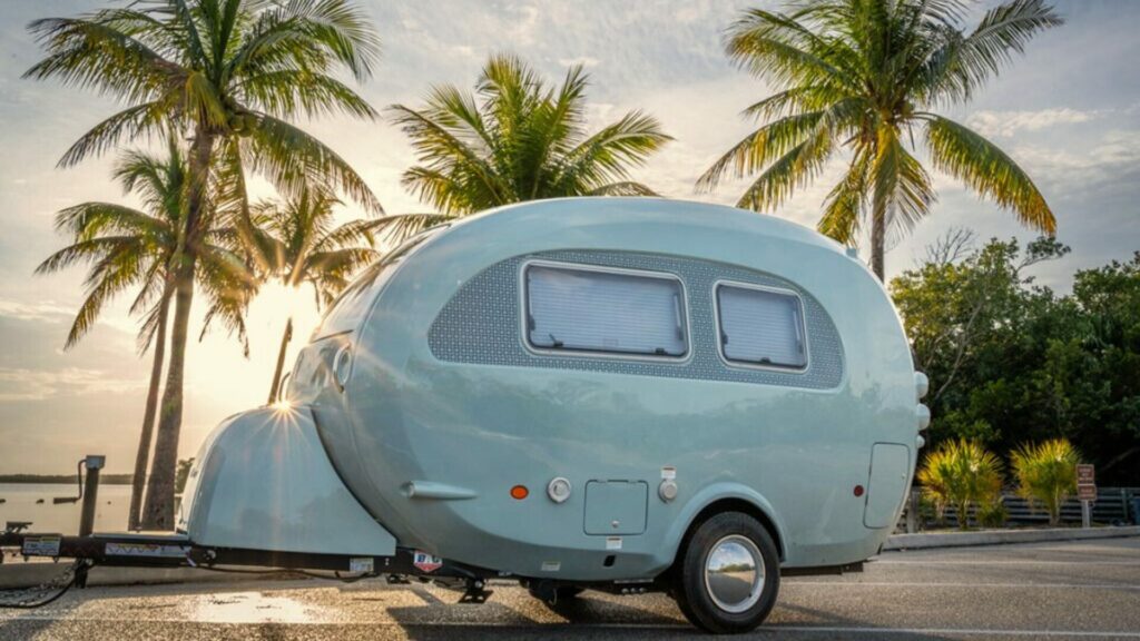 Blue Barefoot camper trailer on the beach by nuCamp.