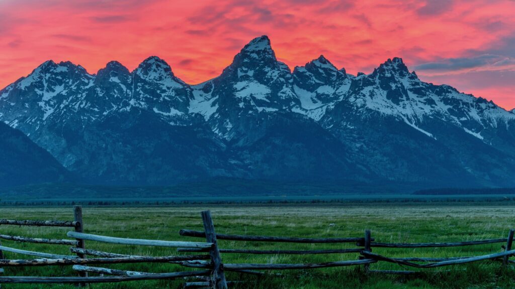 Grand Teton Mountain Range at dusk with a bright red sky in the background. 