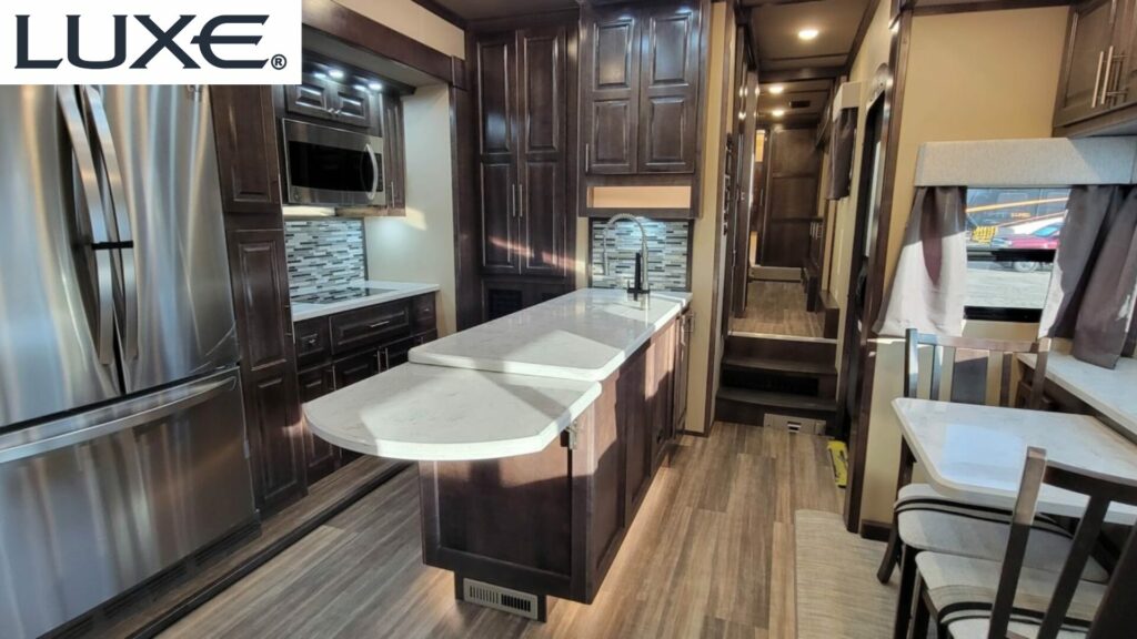 Interior of a Luxe RV showcasing premium woods in the kitchen with residential finishes. 