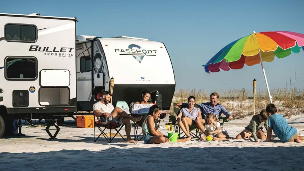 Keystone RVs on a beach with a family playing in the sand.