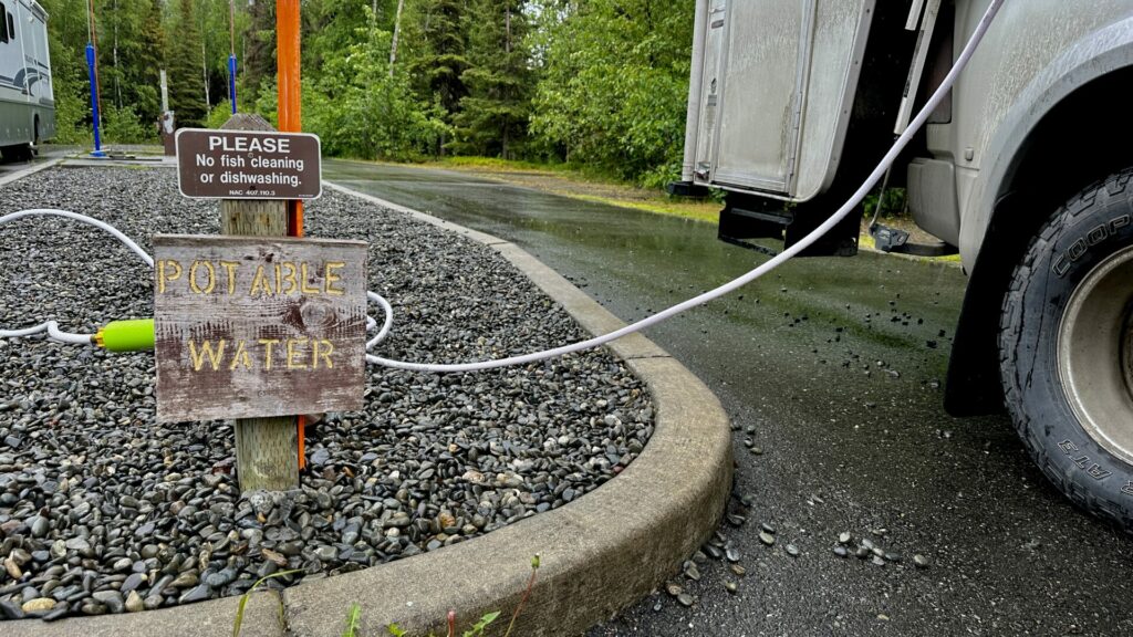 The Camco TastePURE RV fresh water hose connected to our truck camper on one end and the other end connected to a potable water fill station.