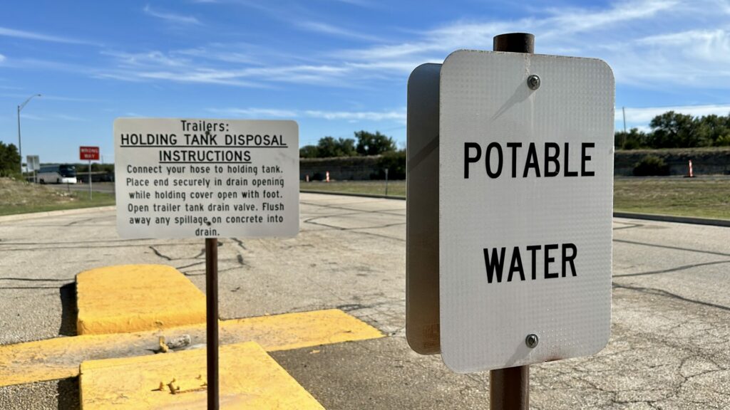 a potable water filling station in an RV park. One sign says "potable water" and another sign gives instructions on how to dump your RV tanks. 