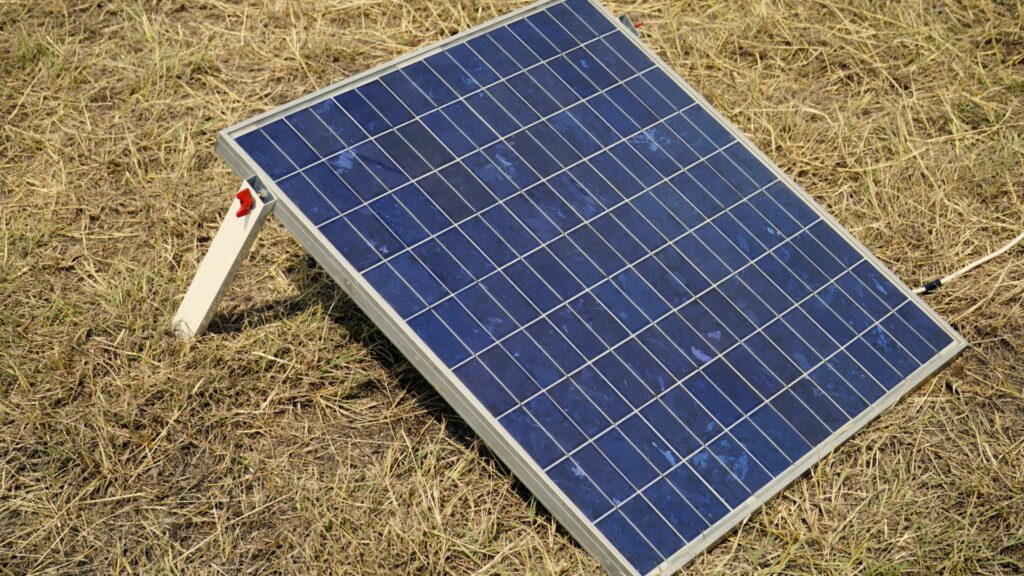 A foldable solar panel setup on the grass in the sun.