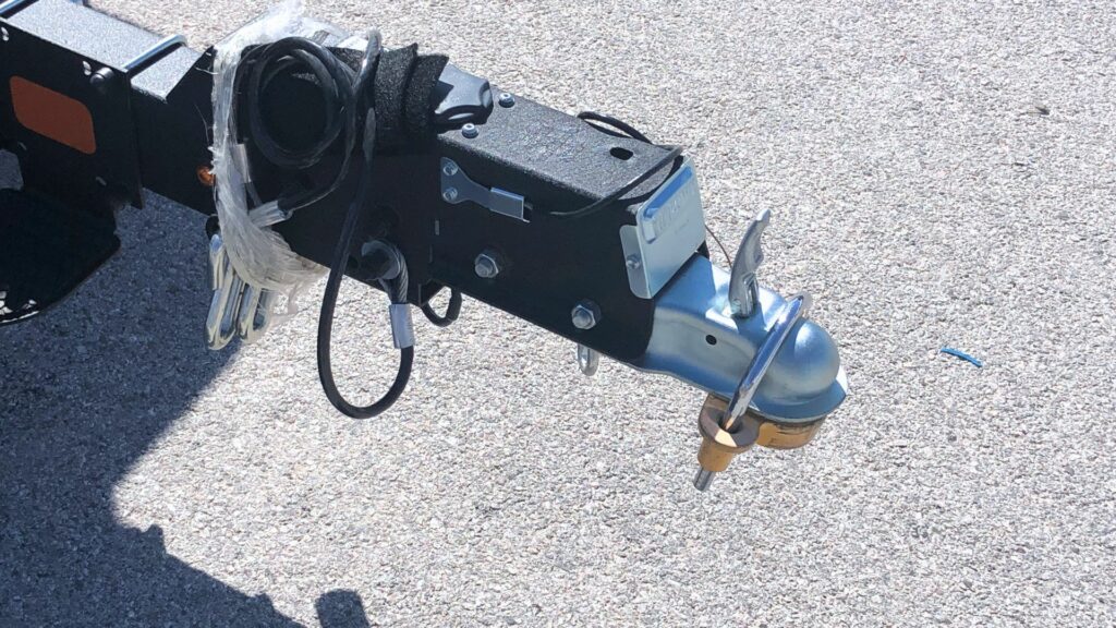 A trailer hitch lock installed on a travel trailer. It is yellow and silver.