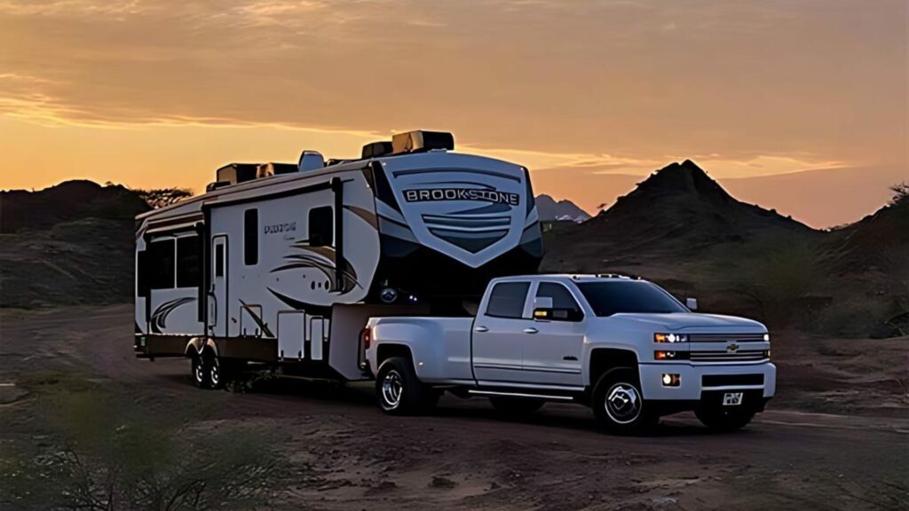 A Coachmen RV Travel Trailer being towed by a Chevy Truck with a sunset background. 