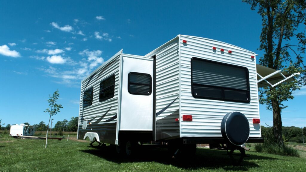 RV with slides out in a field with a blue sky in the background.