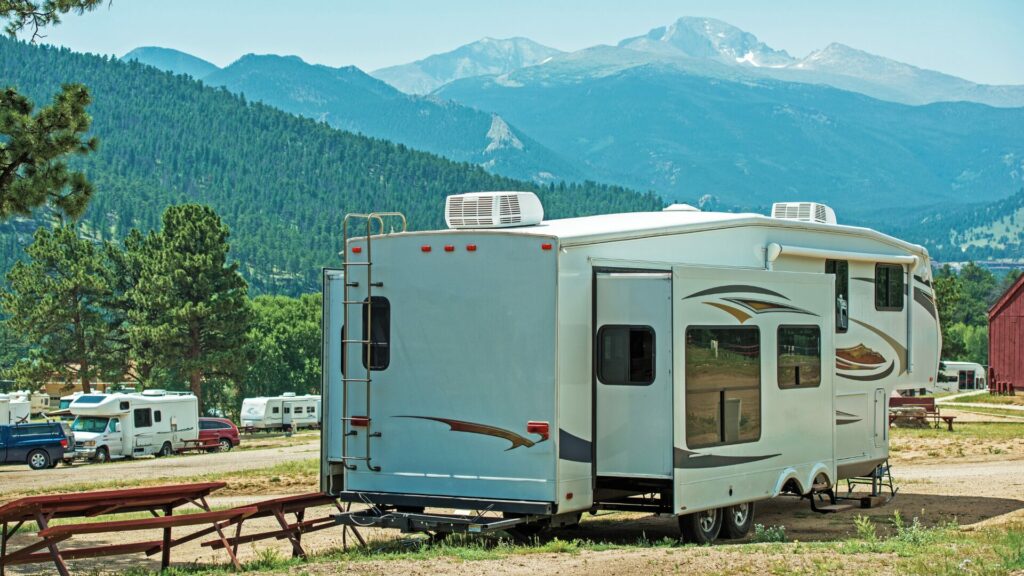 RV with the slides out in an RV park with a mountain range in the background.