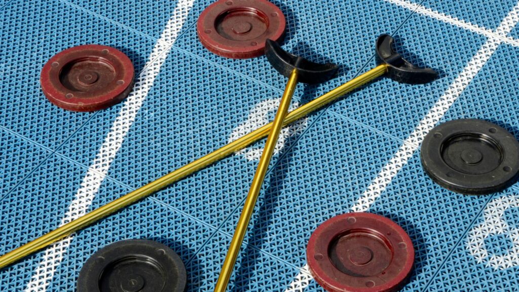 Close-up shot of a shuffleboard board with five shuffle pucks strewn about with two poles at Breezy Hill RV Resort. 