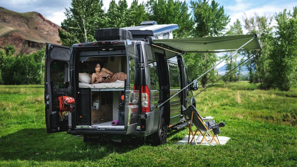 The Airstream Rangeline set up in a grass field with a large rocky mountain behind. 