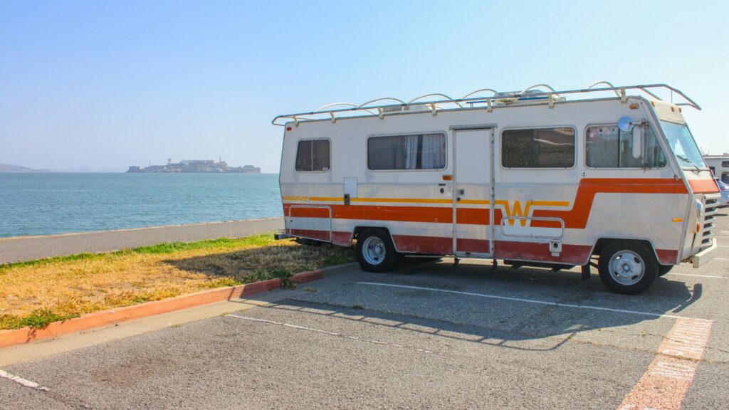 A vintage Winnebago motorhome that backed into a parking spot near the beach.