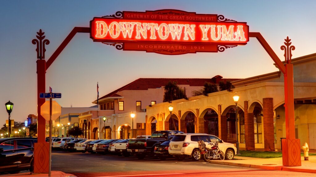 A neon sign stating Downtown Yuma over the area at dusk. 