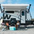 Two people sitting in front of their Winnebago Hike 100 on the beach.