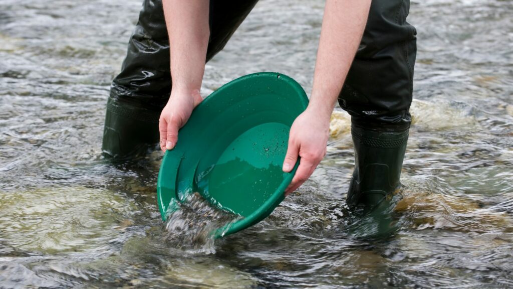 A person panning in a river with waders on. 