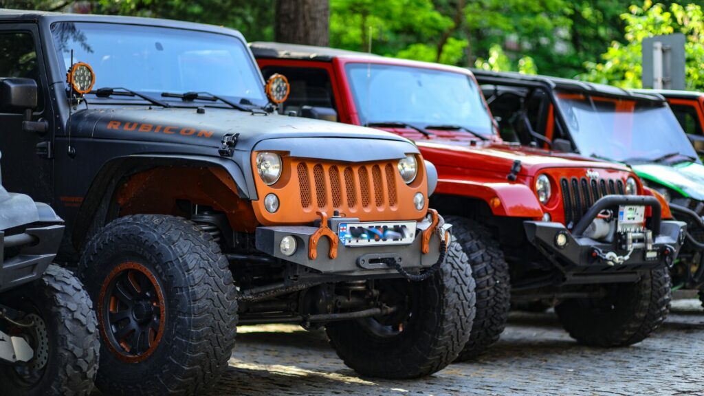 A lineup of Jeep wranglers and ATVs with a wooded background. 