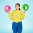 Woman in yellow sweater gesturing "I don't know" with a pink thumbs down in one hand and a green thumbs up in the other.