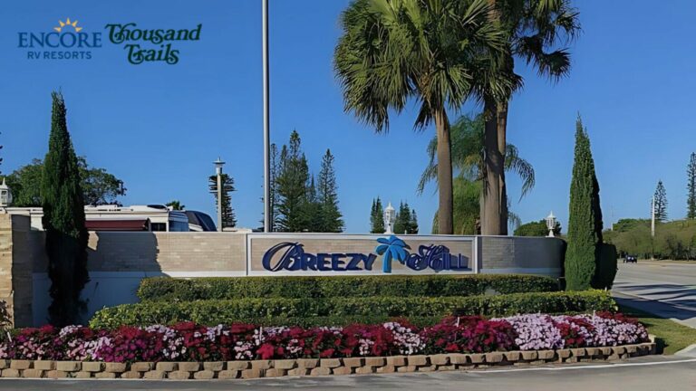 The Breezy Hill Sign with flowers blooming below it and a bright blue sky above it.