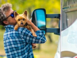 A person holding their Yorkshire Terrier as they stand outside their RV.