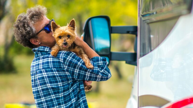 A person holding their Yorkshire Terrier as they stand outside their RV.