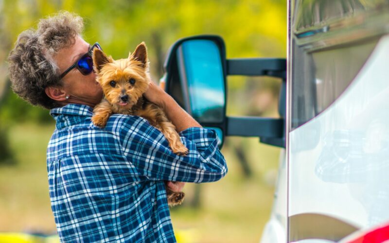 A person holding their Yorkshire Terrier as they stand outside their RV.