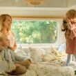 Family of four lounging on a bed in their RV.