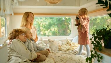 Family of four lounging on a bed in their RV.