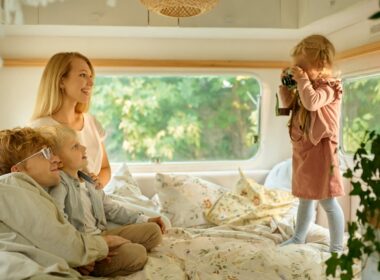 Family of four lounging on a bed in their RV.