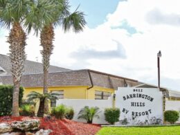 The entrance to Barrington Hills with their signage and three palm trees to the left.