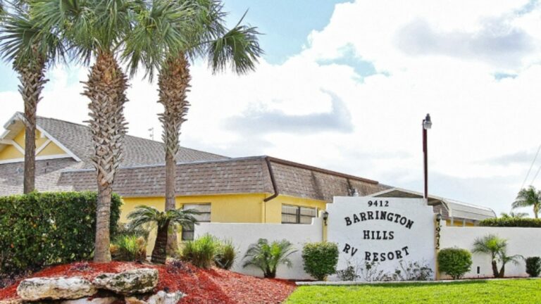 The entrance to Barrington Hills with their signage and three palm trees to the left.