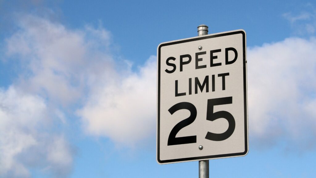 A 25 mph speed limit sign with a blue cloudy sky in the background. 