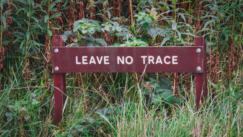 A sign in a heavily grassy area that states "Leave No Trace". 