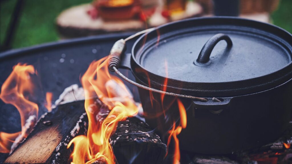 A dutch oven sitting on an open fire. 