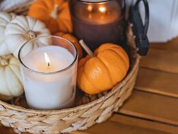 A basket with lit candles and mini pumpkins.