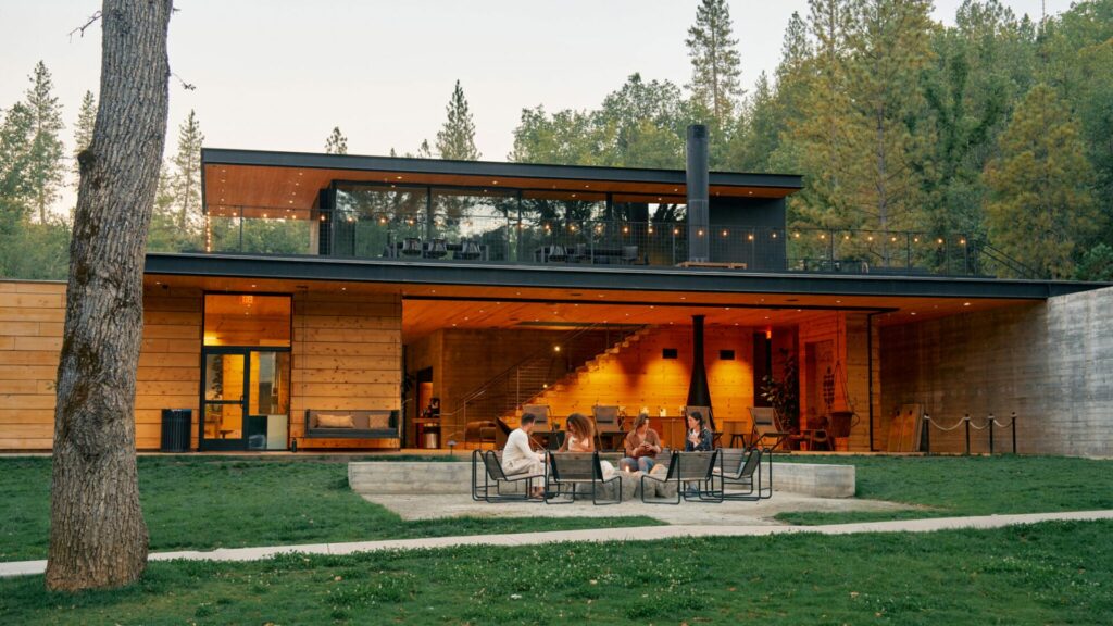 The modern clubhouse at Autocamp Yosemite with people socializing outside. 