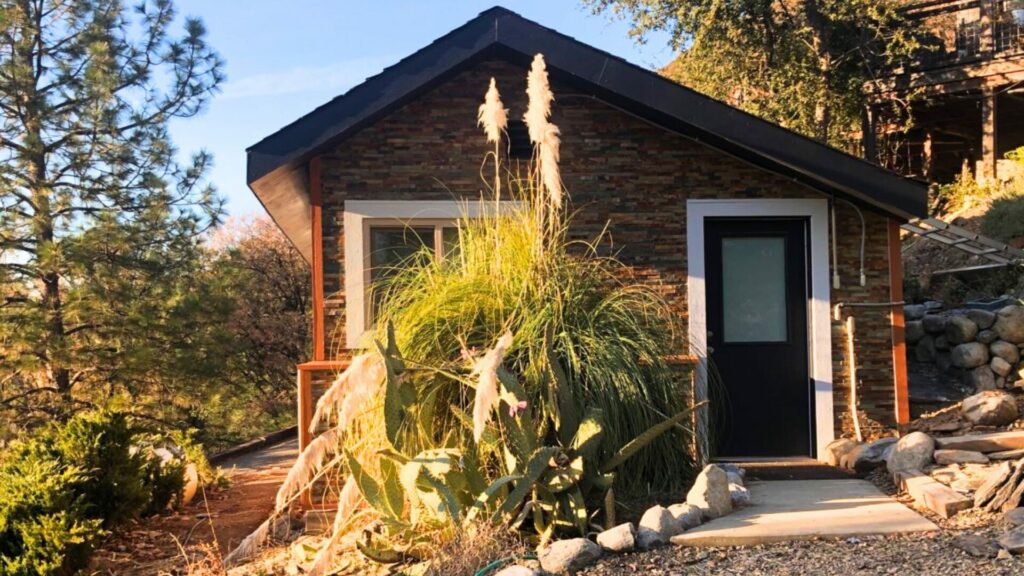 A glamping cabin surrounded by lush plants and forest in Yosemite Bug Rustic Mountian Resort. 