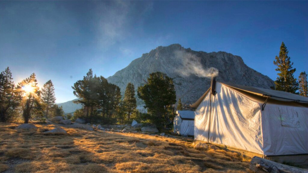 Two High Sierra glamping tents set up within the Yosemite National Park in front of a rocky mountain. 