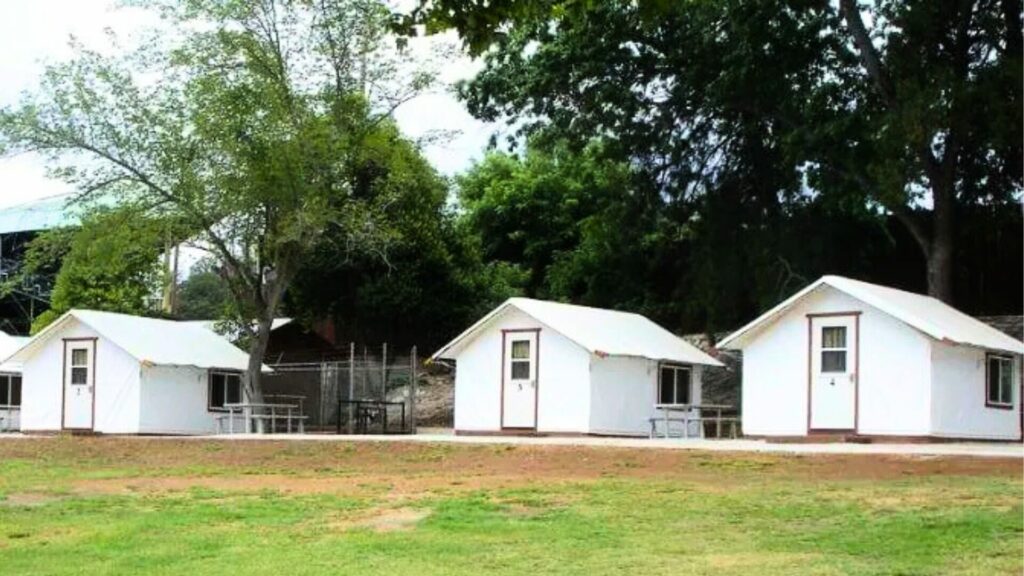 White glamping cabins are set up side by side at the Mariposa Fairground RV Park & Campground near the gateway to Yosemite National Park. 