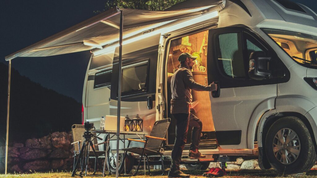 A person standing outside their camper van with a little table set up beside them.