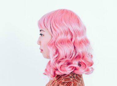 A woman with bright pink hair against a white backdrop.