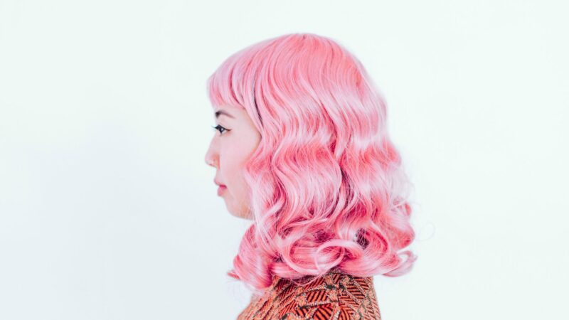 A woman with bright pink hair against a white backdrop.