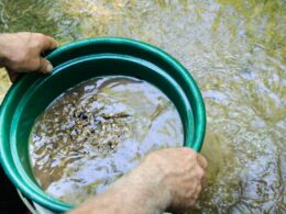 A person using a gold panning kit in the water.