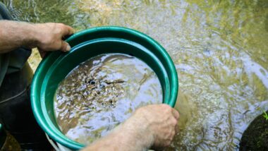 A person using a gold panning kit in the water.