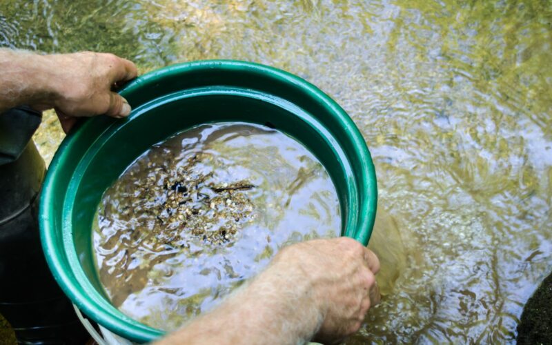 A person using a gold panning kit in the water.