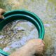 A person using a gold panning kit in the water.