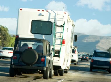 An RV towing a jeep behind it on a highway.