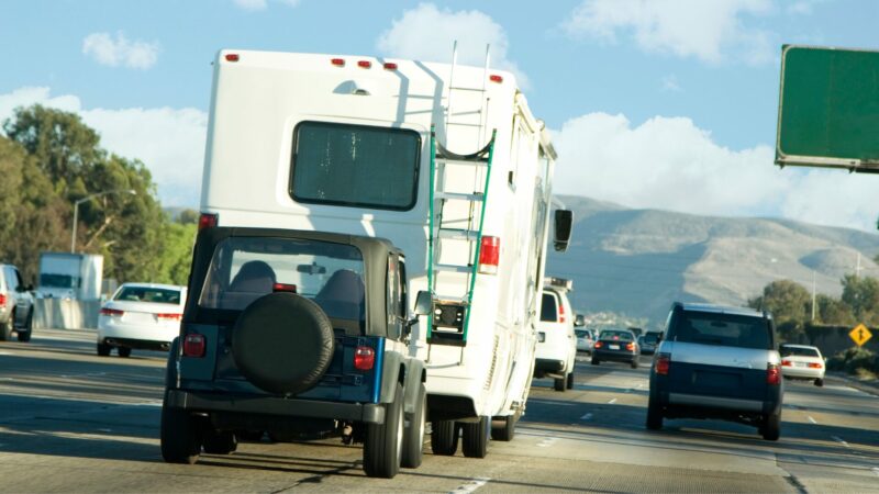 An RV towing a jeep behind it on a highway.