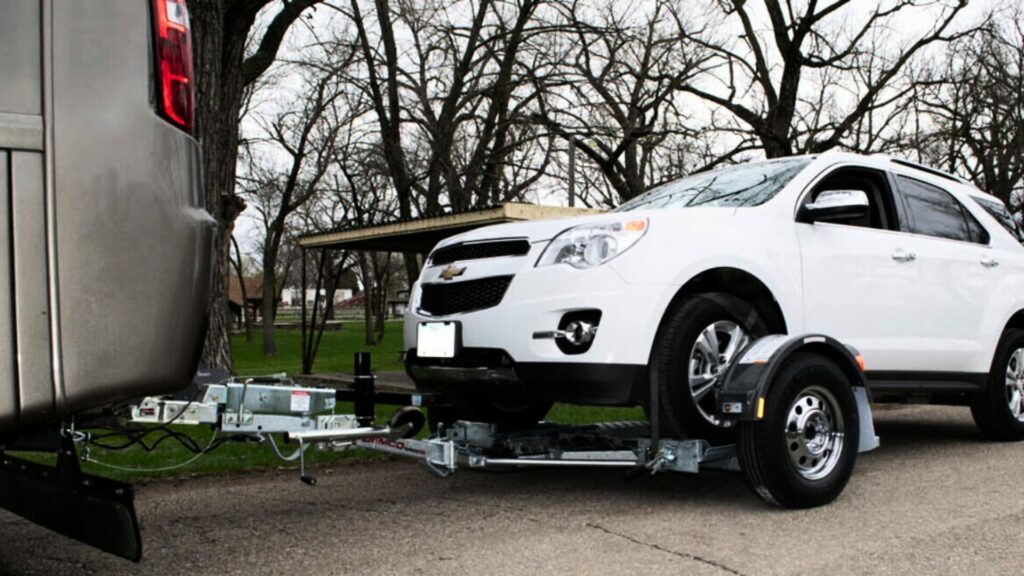 A white Chevy Equinox on a tow dolly in a driveway. 