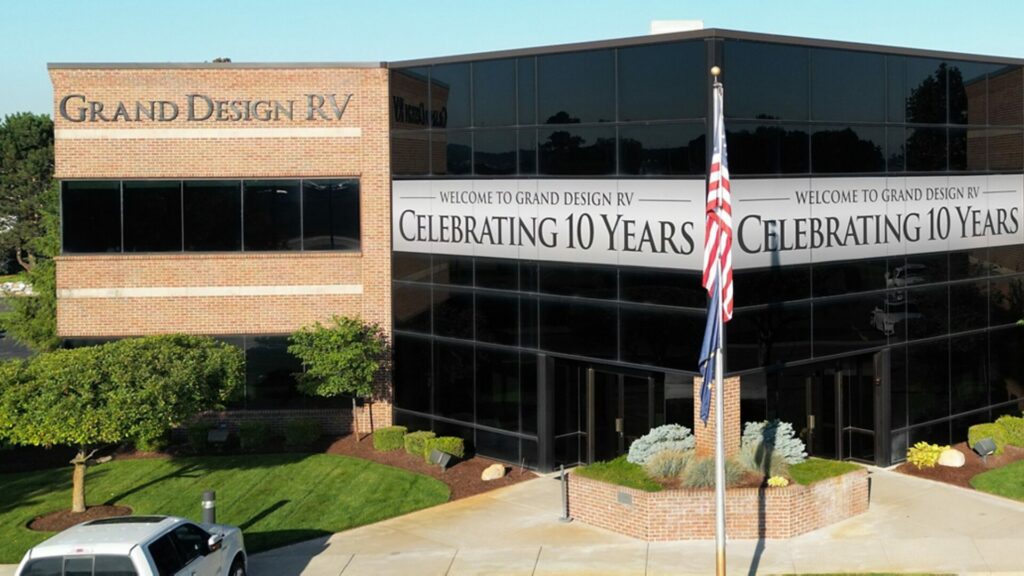 The Grand Design RV headquarters office 3ith a banner over the building stating Welcome to Grand Design RV Celebrating 10 years. 