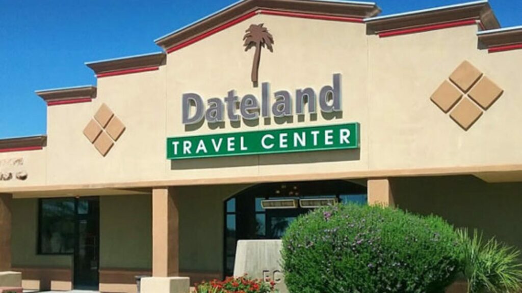 A photo of the Dateland Travel Center building with lush plants in the front. 